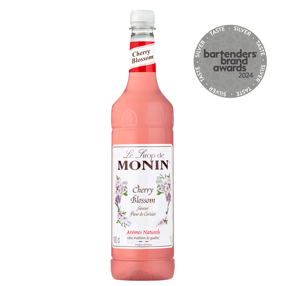 A bottle of MONIN Cherry Blossom syrup, featuring a white label with cherry blossom illustrations and text, captures the essence of Japanese culture. Adorning the display is a medallion marked "bartenders brand awards 2024," encircled by the word "SILVER." This syrup has a light pink hue that evokes the spirit of O-Hanami celebrations.