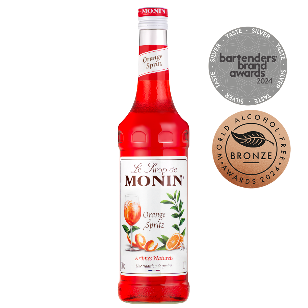 Image of a bottle of MONIN Orange Spritz syrup, a red-orange syrup with a label that features orange slices and green leaves. Perfect for cocktails and mocktails, the bottle is adorned with silver "Bartenders Brand Awards 2024" and bronze "World Alcohol-Free Awards 2024" medals.