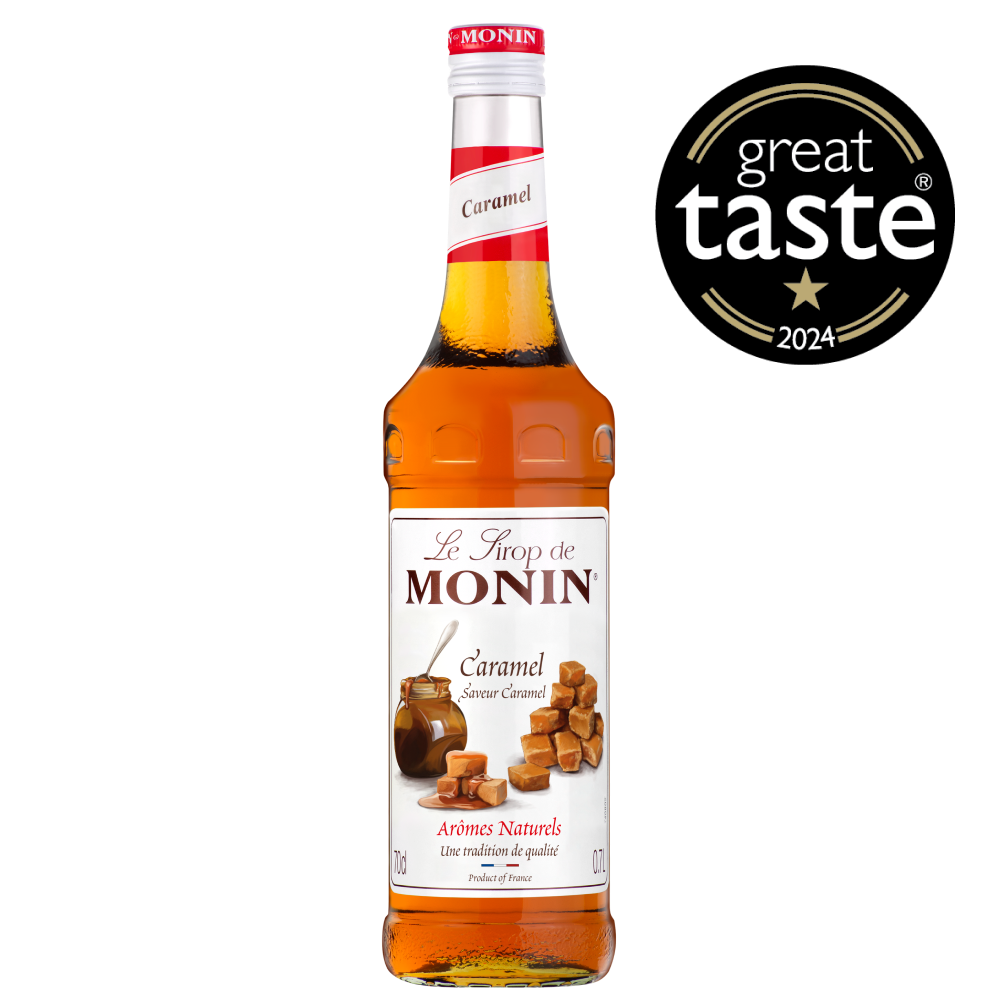 A 0.7L bottle of MONIN Caramel Syrup is displayed. The label reads "Le Sirop de MONIN" and "Caramel" with an image of caramel pieces and caramel sauce, making it a perfect addition to coffee or chocolate. The amber-colored liquid inside the bottle has "Arômes Naturels" and "Product of France" written on the label.