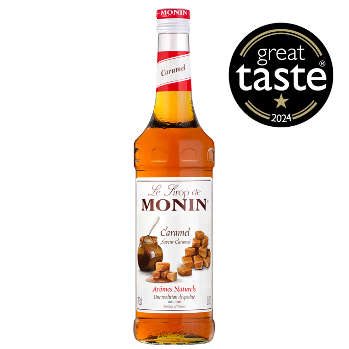 A 0.7L bottle of MONIN Caramel Syrup is displayed. The label reads "Le Sirop de MONIN" and "Caramel" with an image of caramel pieces and caramel sauce, making it a perfect addition to coffee or chocolate. The amber-colored liquid inside the bottle has "Arômes Naturels" and "Product of France" written on the label.